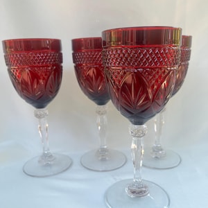 Puede incluir: Un juego de cuatro copas de vino de color rojo rubí con tallo y base de cristal transparente. El cuenco de cada copa presenta un patrón de diamantes texturizado en la parte superior y tallas verticales en forma de hoja en la parte inferior.