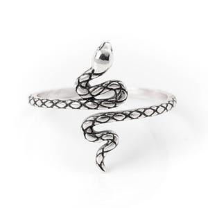 May include: A silver-toned metal ring featuring a wrap-around snake design. The snake body has a detailed, textured scale pattern with darkened grooves to highlight the shape, while the head and tail are smooth and polished, creating a contrast.