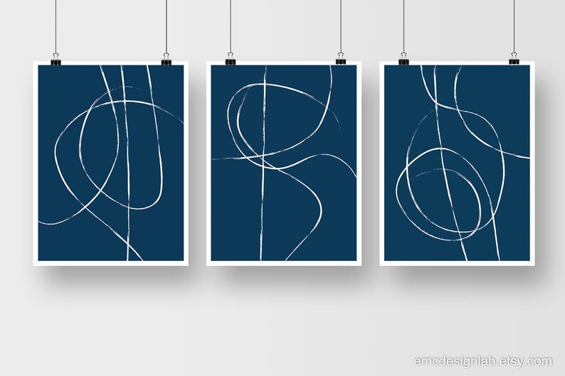 May include: Set of three abstract art prints with white lines on a dark blue background. The lines are simple and organic, creating a modern and minimalist look.