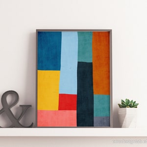May include: Abstract geometric art print with a colorful design featuring shades of blue, red, yellow, orange, and green. The print is framed in a simple black frame.