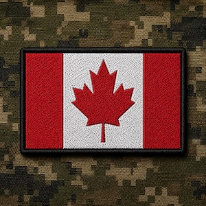 May include: A rectangular embroidered patch featuring the Canadian flag with a central red maple leaf on a white background flanked by two red vertical bars. The patch has a thick black stitched border and a textured fabric appearance.