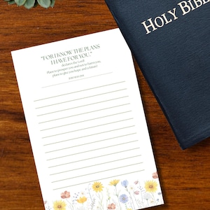 May include: A white notepad with lined paper featuring a floral border at the bottom and the text "FOR I KNOW THE PLANS I HAVE FOR YOU." followed by "declares the Lord! Plans to prosper you and not to harm you, plans to give you hope and a future! JEREMIAH 29:11".