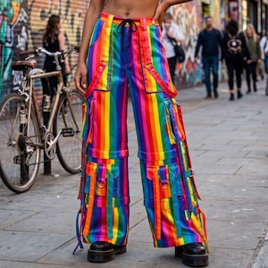 Peut inclure: Pantalon cargo taille haute arborant un motif à rayures verticales arc-en-ciel éclatantes. Ce pantalon large présente de multiples poches utilitaires sur les cuisses, des sangles réglables avec des anneaux en D en métal et un cordon de serrage.
