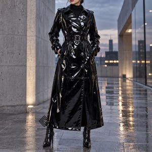May include: A long, black, glossy patent leather trench coat featuring a double-breasted button front, a matching waist belt with a rectangular buckle, epaulets on the shoulders, and long sleeves. The coat has a high collar and a full-length skirt.