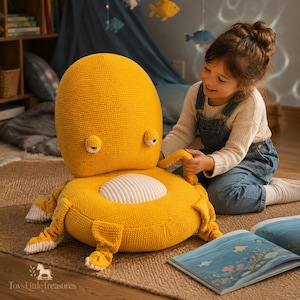 Op de afbeelding: Een groot, geel vloerkussen in de vorm van een octopus met een textuurrijke stoffen oppervlak, een rond wit middenpaneel en twee kleine ogen. De pluche zitting heeft meerdere bungelende tentakels aan de basis voor op de vloer.
