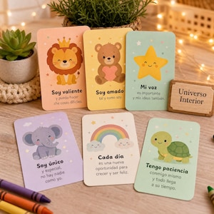 Puede incluir: Un conjunto de seis tarjetas de afirmación rectangulares con ilustraciones coloridas de un león, un oso, una estrella, un elefante, un arcoíris y una tortuga. Cada tarjeta muestra texto en español y un pequeño letrero de madera Universo Interior.
