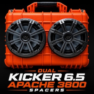 May include: A bright orange hard-shell case featuring two black Kicker 6.5 speakers mounted on the front. The text DUAL KICKER 6.5 APACHE 3800 SPACERS is printed in white and orange below the case, which has a top handle and ribbed design.