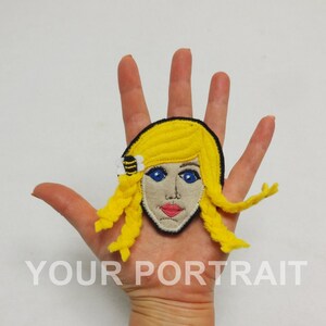 May include: A yellow felt portrait of a person with blonde hair and blue eyes. The portrait is on a white background and has the text "YOUR PORTRAIT" below it.