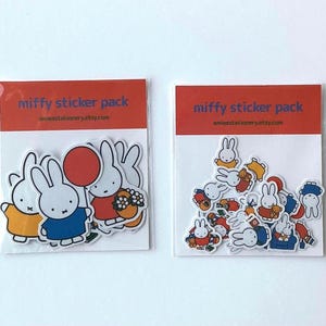 Könnte beinhalten: Zwei durchsichtige Kunststoffverpackungen mit der Aufschrift miffy sticker pack und einem orangefarbenen Kopfbereich. Die linke Packung enthält größere gestanzte Aufkleber eines weißen Hasen. Die rechte Packung enthält kleinere Aufkleber.