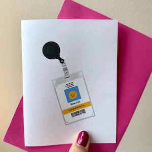 Może przedstawiać: Biała kartka okolicznościowa z grafiką czarnego, zwijanego uchwytu na identyfikator przymocowanego do przezroczystego plastikowego etui. Karta wewnątrz przedstawia niebieski kwadrat z żółtą buźką oraz tekst New Job, Congratulations i So Proud Of You.