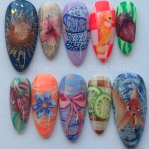 Peut inclure: Dix faux ongles en forme d'amande avec des motifs peints à la main, notamment un soleil, une fleur d'hibiscus, des tasses, un hippocampe, une fraise, un crabe, une fleur bleue, un nœud rose, des citrons verts et un poisson rouge.