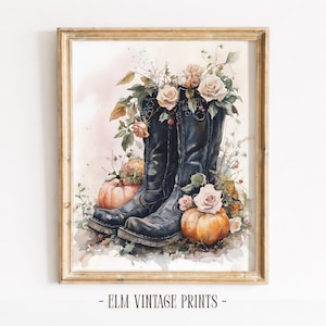 Pode incluir: Uma impressão em aguarela emoldurada apresentando um par de botas de couro preto preenchidas com rosas rosa-pálido e folhagem verde, rodeadas por abóboras cor de laranja e folhas de outono. O texto ELM VINTAGE PRINTS está na base da moldura.