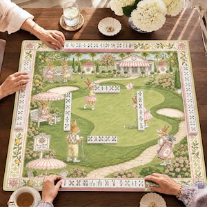 May include: A square mahjong mat featuring a golf course illustration with rabbits playing golf, surrounded by a decorative border. The mat includes rows of white mahjong tiles with red and black symbols arranged on the surface for gameplay.
