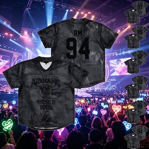 Op de afbeelding: Een zwart honkbalshirt met korte mouwen, knoopsluiting en een mesh-textuur. De voorzijde is voorzien van de tekst ARIRANG WORLD TOUR. De achterzijde toont de letters RM en het getal 94 in een groot zwart lettertype met een subtiel patroon.