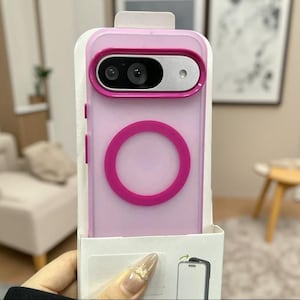 Puede incluir: Una funda para smartphone de color rosa claro con un anillo magnético circular de color rosa oscuro en la parte posterior y un bisel de cámara elevado de color rosa oscuro. La funda viene en un empaque blanco con un gráfico de instalación.