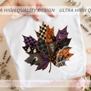 May include: A white t-shirt featuring a large, detailed maple leaf graphic composed of various Halloween-themed patterns. The leaf design includes images of ghosts, a skull, a tombstone, pumpkins, a crow, bats, and spiderwebs in purple, orange, and black.
