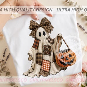 May include: A white t-shirt featuring a graphic of a ghost wearing a large leopard print bow. The ghost is designed with a patchwork pattern of plaid, floral, and animal print fabrics and is holding a small orange jack-o'-lantern pumpkin bucket.