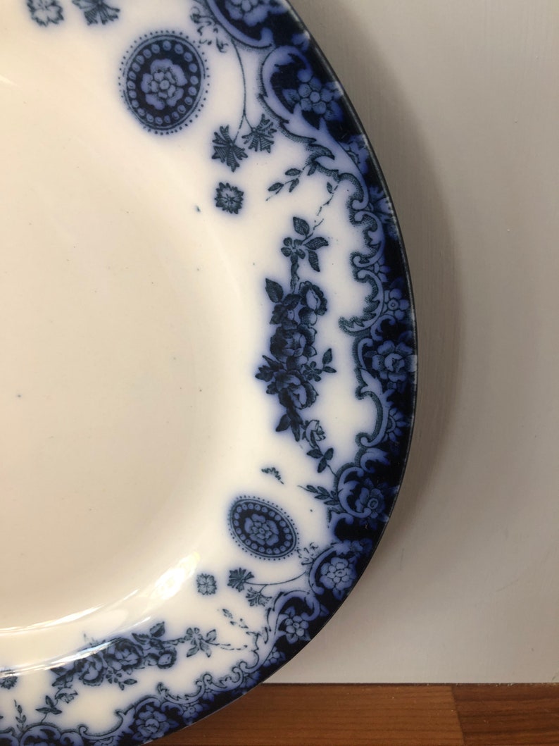 May include: A white ceramic plate with a blue and white floral pattern around the edge.