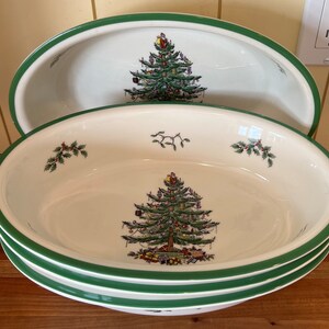 May include: Three white oval ceramic serving bowls with green trim. Each bowl features a colorful Christmas tree design.