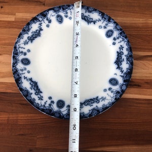 May include: A blue and white porcelain dinner plate with a floral design. The plate measures 10 inches in diameter.