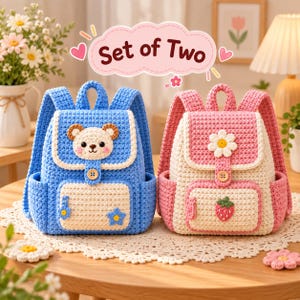 Può includere: Un set di due zaini all'uncinetto. Lo zaino blu presenta un muso d'orso sulla patta e una piccola stella blu. Lo zaino rosa presenta una margherita bianca sulla patta e un motivo a fragola. Entrambi hanno bottoni in legno e tasche color crema.