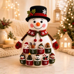 Op de afbeelding: Een gehaakte sneeuwpop-adventskalender met een zwarte hoge hoed versierd met hulst en een sneeuwvlok, een wit lichaam en rode wanten. De sneeuwpop heeft kleine zakjes genummerd 1, 2, 5, 8, 9, 14, 17 en 18 met kleine gehaakte kerstfiguren.