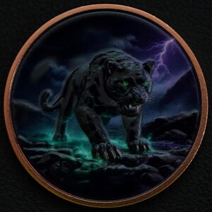 May include: A circular copper-toned coin featuring a detailed illustration of a black panther with glowing green eyes. The panther is walking across a dark, rocky landscape with a purple lightning bolt in the background and teal light effects.