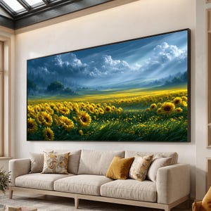 Può includere: Una grande stampa artistica rettangolare da parete che raffigura un vivace paesaggio di girasoli gialli in un campo sotto un drammatico cielo blu con nuvole bianche. L'opera è incorniciata in un sottile bordo nero su una parete chiara sopra un divano.