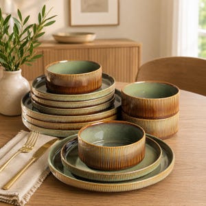 May include: A set of ceramic dinnerware featuring a ribbed exterior texture with a gradient finish transitioning from a deep brown base to a soft sage green interior. The collection includes stacked round plates and matching deep bowls.