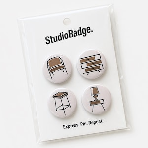 May include: A set of four round pin-back buttons on a white display card labeled StudioBadge. and Express. Pin. Repeat. Each button features a brown and black line art illustration of furniture, including a chair, a dresser, a stool, and a lamp.