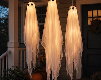 May include: Three hanging ghost decorations made of sheer white fabric, each featuring two black circular eyes and an internal warm light source that illuminates the translucent material, creating a glowing effect for outdoor display.