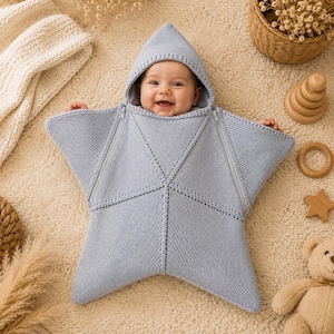 Peut inclure: Une gigoteuse pour bébé en forme d'étoile tricotée en bleu clair avec une capuche. La gigoteuse présente un motif de couture centrale et deux fermetures éclair diagonales partant du cou vers les pointes de l'étoile pour un accès facile.