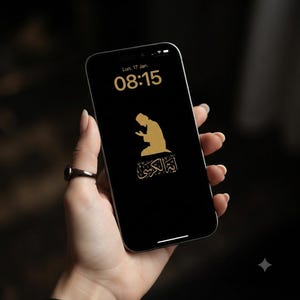 May include: A smartphone with a black screen displaying the time 08:15, the date Lun. 17 Jan., a gold silhouette of a person kneeling in prayer, and gold Arabic calligraphy text below the figure. The device has a thin black frame and rounded corners.