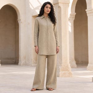 Op de afbeelding: Een beige overhemd met lange mouwen, knoopsluiting en een klassieke kraag, gecombineerd met een bijpassende broek met wijde pijpen. De set is gemaakt van een effen stof met een zichtbare weving, een rechte zoom en een losse, relaxte pasvorm.