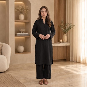 May include: A solid black long-sleeved tunic featuring a mandarin collar with a vertical row of matching buttons down the center, paired with matching wide-leg trousers and brown open-toe sandals, creating a coordinated two-piece outfit.