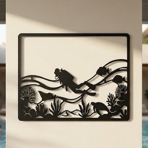 May include: A rectangular black metal wall art piece featuring a silhouette of a scuba diver swimming underwater among coral reefs, sea plants, a sea turtle, and several fish, all enclosed within a thin, solid black rectangular frame border.
