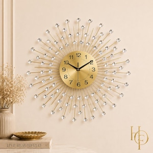 May include: A sunburst wall clock featuring a circular gold face with black numerals and hands. Thin gold metal spokes radiate outward from the center, each tipped with a clear, faceted crystal accent, creating a starburst design.