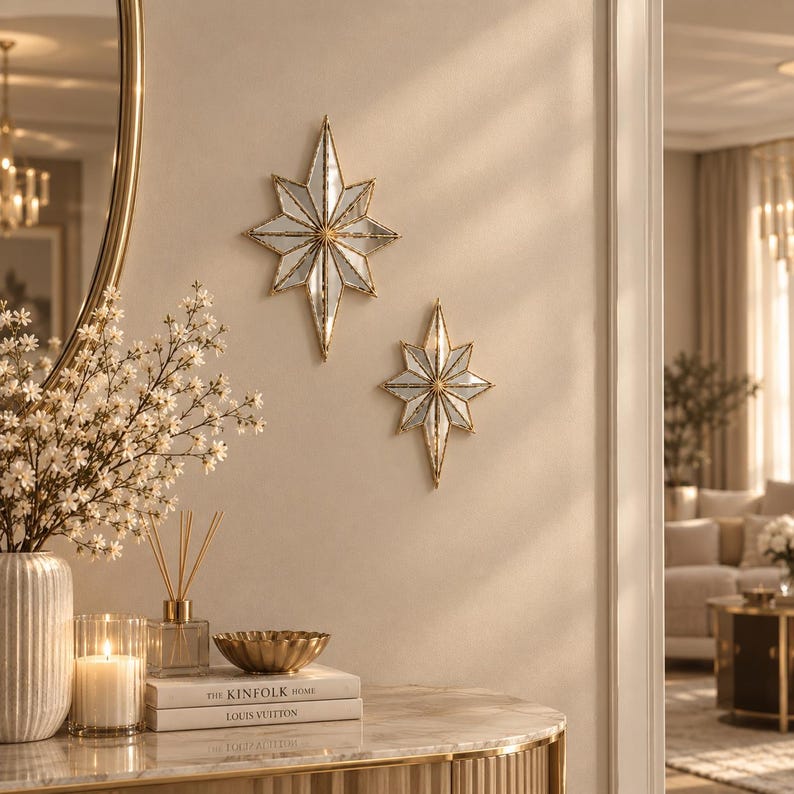 May include: Two star-shaped wall mirrors with gold-toned metal frames and faceted glass panels. The larger mirror is positioned above the smaller one, both featuring a multi-pointed design that reflects light across the wall surface.