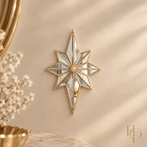 May include: A star-shaped wall mirror featuring a gold-toned frame with a textured, beaded edge. The mirror consists of multiple triangular glass segments arranged in a radial pattern, creating a pointed, multi-faceted star design on the wall.