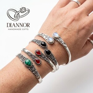 Peut inclure: Quatre bracelets manchettes en argent avec un travail de filigrane complexe et des pierres précieuses en forme de goutte. Les pierres incluent de la malachite verte, de la cornaline rouge, de l'onyx noir et de la pierre de lune irisée.
