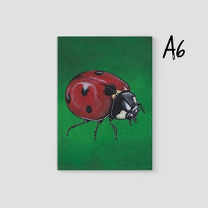 Puede incluir: Impresión tamaño A6 con una ilustración detallada de una mariquita roja con puntos negros y cabeza negra, sobre un fondo verde vibrante. La mariquita es el punto focal, mostrando sus intrincados detalles. El texto "A6" está en la esquina superior derecha.