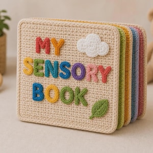 Puede incluir: Un libro sensorial cuadrado de ganchillo beige con letras cosidas multicolores que dicen MY SENSORY BOOK. La portada presenta una nube de ganchillo blanca y una aplicación de hoja verde. El libro tiene varias páginas en tonos verde, amarillo, azul y rosa.