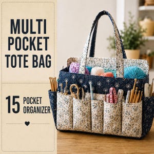 Op de afbeelding: Een multifunctionele tas met 15 vakken, gemaakt van donkerblauwe stof met een wit paardenbloemmotief en een contrasterende crèmekleurige stof met een klein bloemenprintje. De tas bevat diverse breinaalden, garen en scharen.