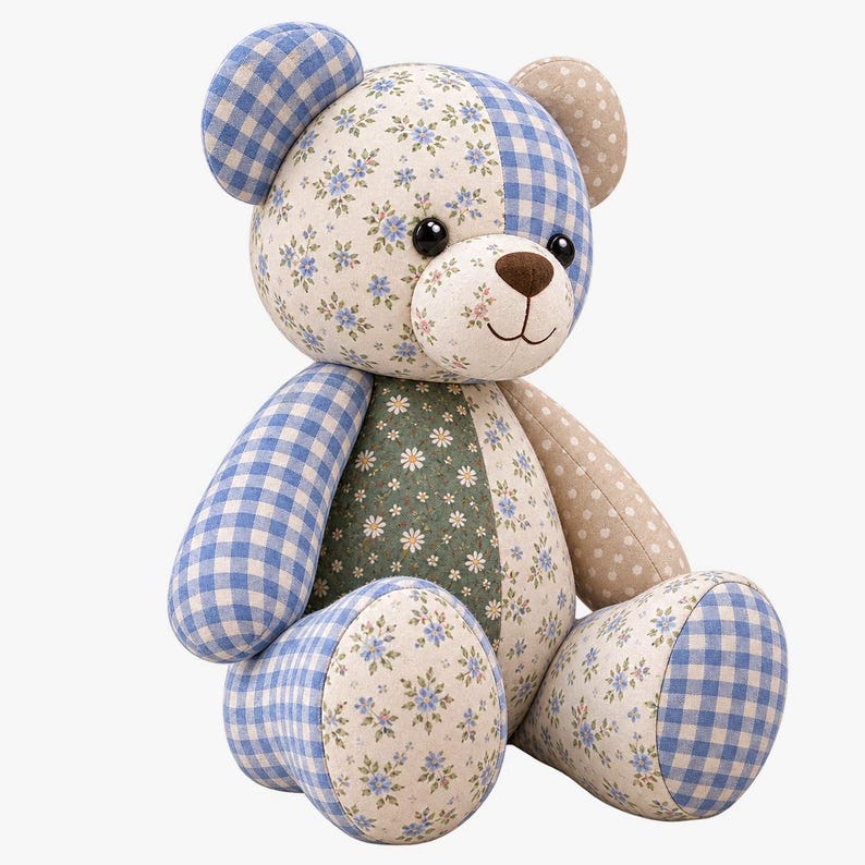 K&ouml;nnte beinhalten: Ein Stoffteddyb&auml;r aus verschiedenen Stoffst&uuml;cken. Der B&auml;r zeigt blau-wei&szlig;es Vichy-Karo, cremefarbenen Stoff mit kleinen blauen Blumenmustern, dunkelgr&uuml;nen Stoff mit wei&szlig;en G&auml;nsebl&uuml;mchen und beigen Stoff mit wei&szlig;en Punkten.