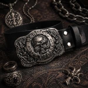 Könnte beinhalten: Ein schwarzer Ledergürtel mit einer rechteckigen, silberfarbenen Metallschnalle, die ein zentrales Totenkopfmotiv, Flammendetails und den geprägten Schriftzug Harley Davidson 19 03 aufweist. Der Gürtel ist mit silbernen Nieten und Schmuck versehen.