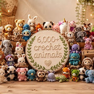 May include: A collection of small, multicoloured crocheted animal figures arranged around a circular embroidery hoop featuring the stitched text 6,000+ crochet animals and a heart, all displayed on a wooden surface with greenery.