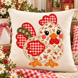 May include: A square off-white throw pillow featuring an embroidered chicken design. The chicken has a red and white checkered comb and wing, a green floral tail, and a body patterned with small red flowers on an off-white background.