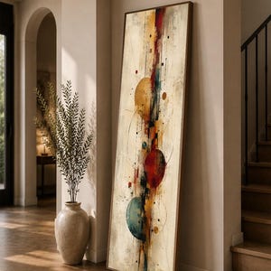 May include: A tall, rectangular framed wall art piece featuring an abstract composition. The design includes vertical lines, scattered dots, and three prominent circular shapes in gold, red, and teal, set against a textured cream background.