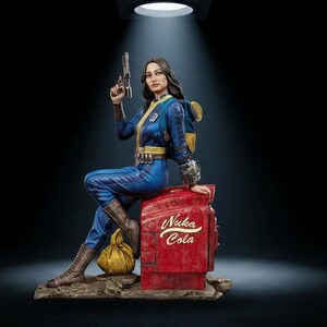 May include: A detailed figurine of a character wearing a blue and yellow jumpsuit with a backpack, sitting on a red Nuka Cola vending machine. The character holds a pistol in one hand and wears brown boots, with a yellow bag resting on the base.
