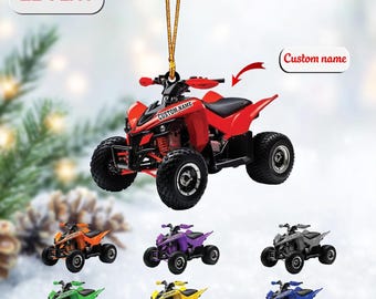 May include: A 2D flat hanging ornament shaped like an ATV with a gold string. The main ATV is red with black tires and the text CUSTOM NAME. Below are six smaller ATV ornaments in orange, purple, gray, green, yellow, and blue, each with the text CUSTOM NAME.